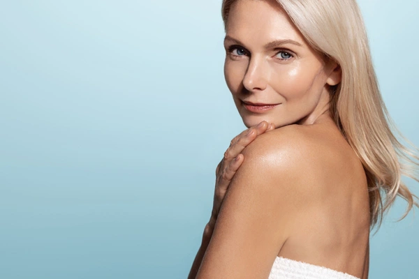 Piękna dojrzała kobieta prezentuje zadbaną, rozświetloną cerę